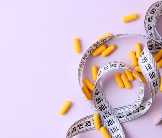 measuring-tape-diet-pills-colored-background-closeup_441923-2421